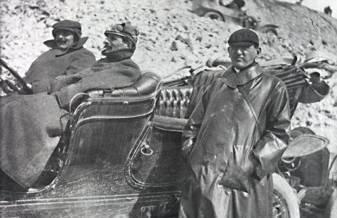 Early motorists beside an automobile